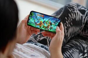 Clash of Clans mobile iOS game on iPhone 15 smartphone screen in female hands during mobile gameplay photo