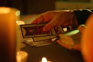 KYIV, UKRAINE - JULY 10, 2024 Tarot reader picking tarot cards. Candlelight in dark room. Tarot reader or fortune teller reading and forecasting photo