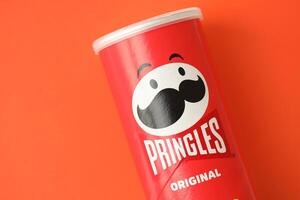 KYIV, UKRAINE - APRIL 20, 2024 Pringles original potato chips on red background. Pringles is a brand of potato snack chips photo