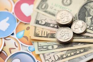 KYIV, UKRAINE - APRIL 20, 2024 USD dollars money and large set of stickers with Emoji yellow faces. The concept of smm, smo paid service for boost in social media photo