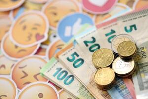 KYIV, UKRAINE - APRIL 20, 2024 European euro money and large set of stickers with Emoji yellow faces. The concept of smm, smo paid service for boost in social media photo