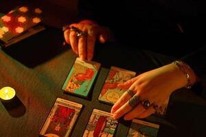 KYIV, UKRAINE - JULY 10, 2024 Tarot reader picking tarot cards. Candlelight in dark room. Tarot reader or fortune teller reading and forecasting photo
