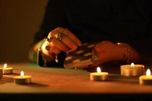 KYIV, UKRAINE - JULY 10, 2024 Tarot reader picking tarot cards. Candlelight in dark room. Tarot reader or fortune teller reading and forecasting photo
