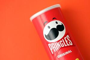 KYIV, UKRAINE - APRIL 20, 2024 Pringles original potato chips on red background. Pringles is a brand of potato snack chips photo