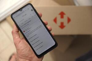 KYIV, UKRAINE - APRIL 20, 2024 Nova Poshta Logotype on cardboard box and website on smartphone screen. Nova Poshta is best ukrainian postal service company photo