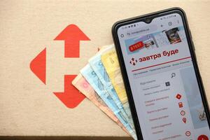 KYIV, UKRAINE - APRIL 20, 2024 Nova Poshta Logotype on cardboard box and website on smartphone screen. Nova Poshta is best ukrainian postal service company photo