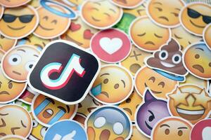 KYIV, UKRAINE - APRIL 20, 2024 TikTok logo and large set of stickers with Emoji yellow faces. Emoji is a pictogram or smiley embedded in text and used in electronic messages photo