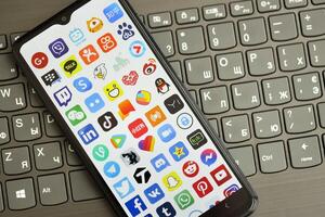 KYIV, UKRAINE - APRIL 1, 2024 Many apps icon on smartphone screen on black keyboard photo