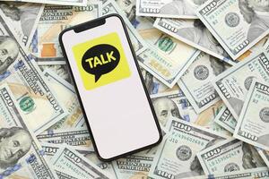 KYIV, UKRAINE - APRIL 1, 2024 KakaoTalk messenger icon on smartphone screen on many usd money bills photo