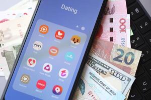KYIV, UKRAINE - FEBRUARY 28, 2024 Dating apps icons on smartphone display and money bills photo