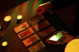 KYIV, UKRAINE - JULY 10, 2024 Tarot reader picking tarot cards. Candlelight in dark room. Tarot reader or fortune teller reading and forecasting photo