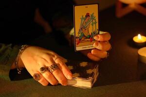 KYIV, UKRAINE - JULY 10, 2024 Tarot reader picking tarot cards. Candlelight in dark room. Tarot reader or fortune teller reading and forecasting photo