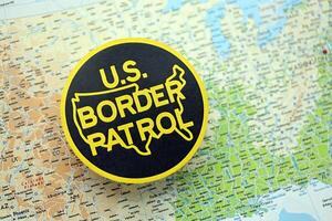 KYIV, UKRAINE - JUNE 26, 2024 U.S. Border Patrol coat of arms on paper map of United States photo
