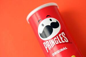 KYIV, UKRAINE - APRIL 20, 2024 Pringles original potato chips on red background. Pringles is a brand of potato snack chips photo