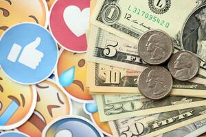 KYIV, UKRAINE - APRIL 20, 2024 USD dollars money and large set of stickers with Emoji yellow faces. The concept of smm, smo paid service for boost in social media photo