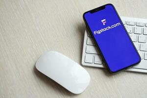 KYIV, UKRAINE - MARCH 17, 2024 Figstack logo on iPhone display screen with apple keyboard and mouse on table photo