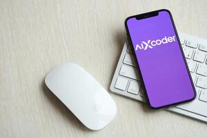 KYIV, UKRAINE - MARCH 17, 2024 AIXcoder logo on iPhone display screen with apple keyboard and mouse on table photo