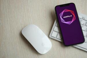 KYIV, UKRAINE - MARCH 17, 2024 StabilityAI logo on iPhone display screen with apple keyboard and mouse on table photo