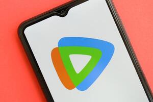 KYIV, UKRAINE - APRIL 1, 2024 Tencent WeTV icon on smartphone screen on red table photo