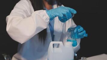 Close-up of a scientist's hands holding a flask with pink liquid in a lab. video