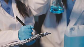 Close-up of a scientist's hands holding a flask with pink liquid in a lab. video