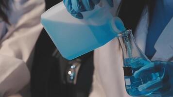 Close-up of a scientist's hands holding a flask with pink liquid in a lab. video