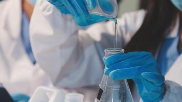 Close-up of a scientist's hands holding a flask with pink liquid in a lab. video