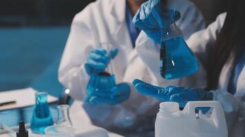 Close-up of a scientist's hands holding a flask with pink liquid in a lab. video