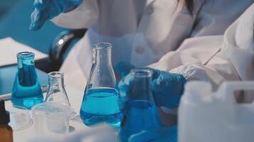 Close-up of a scientist's hands holding a flask with pink liquid in a lab. video