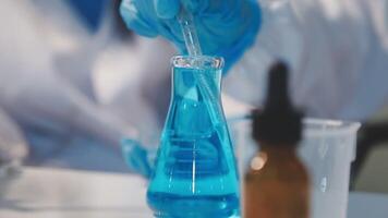Close-up of a scientist's hands holding a flask with pink liquid in a lab. video