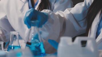 Close-up of a scientist's hands holding a flask with pink liquid in a lab. video