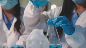 Close-up of a scientist's hands holding a flask with pink liquid in a lab. video