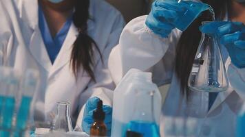 Close-up of a scientist's hands holding a flask with pink liquid in a lab. video