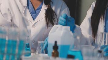 Close-up of a scientist's hands holding a flask with pink liquid in a lab. video