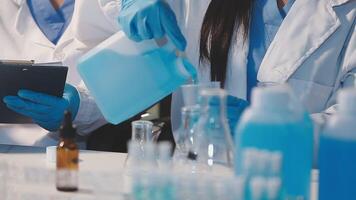 Close-up of a scientist's hands holding a flask with pink liquid in a lab. video