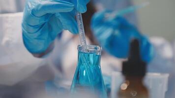 Close-up of a scientist's hands holding a flask with pink liquid in a lab. video