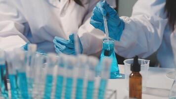 Close-up of a scientist's hands holding a flask with pink liquid in a lab. video