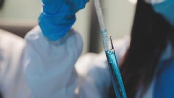 Close-up of a scientist's hands holding a flask with pink liquid in a lab. video