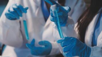 Close-up of a scientist's hands holding a flask with pink liquid in a lab. video