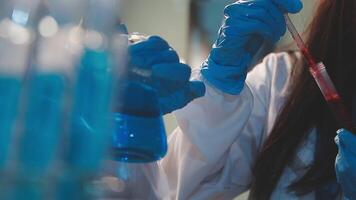 Close-up of a scientist's hands holding a flask with pink liquid in a lab. video