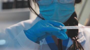 Close-up of a scientist's hands holding a flask with pink liquid in a lab. video