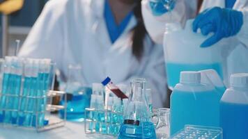 Close-up of a scientist's hands holding a flask with pink liquid in a lab. video