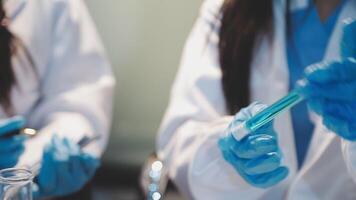 Close-up of a scientist's hands holding a flask with pink liquid in a lab. video
