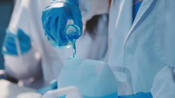 Close-up of a scientist's hands holding a flask with pink liquid in a lab. video