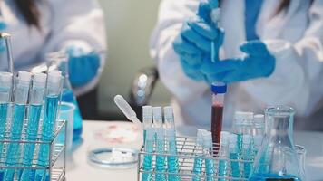 Close-up of a scientist's hands holding a flask with pink liquid in a lab. video