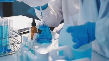 Close-up of a scientist's hands holding a flask with pink liquid in a lab. video