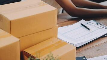 Startup small business SME, Entrepreneur owner African woman using smartphone or tablet taking receive and checking online purchase shopping order to preparing pack product box. video