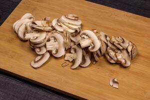 Mushrooms on a cutting board during cleaning and cutting as part of the process of preparing fresh champignons for freezing photo
