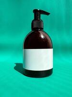 Mockup of a brown plastic bottle with a black dispenser and a white label on a bright turquoise background. photo