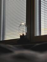The lamp on the windowsill in front of the window with jalousie, the sunset or sun rise light photo